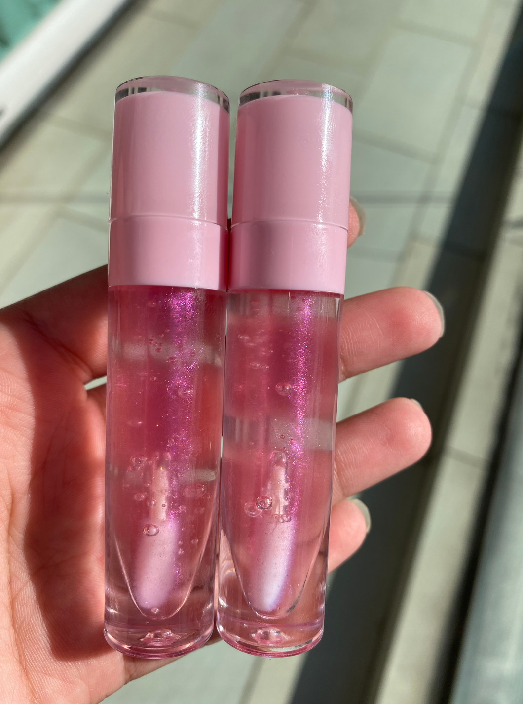 Picture of a light pink clear gloss in a pink tube.